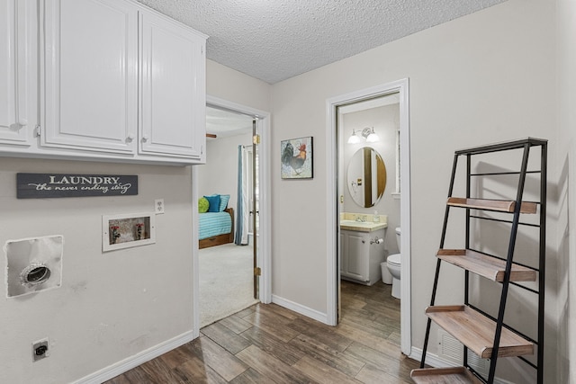 laundry area with cabinets, hookup for an electric dryer, washer hookup, a textured ceiling, and hardwood / wood-style floors