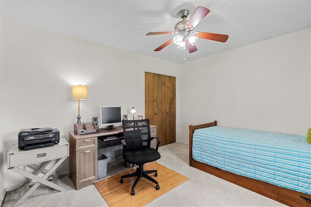 bedroom with a textured ceiling, ceiling fan, light colored carpet, and a closet