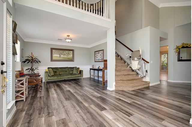 entrance foyer with wood-type flooring, a towering ceiling, and ornamental molding