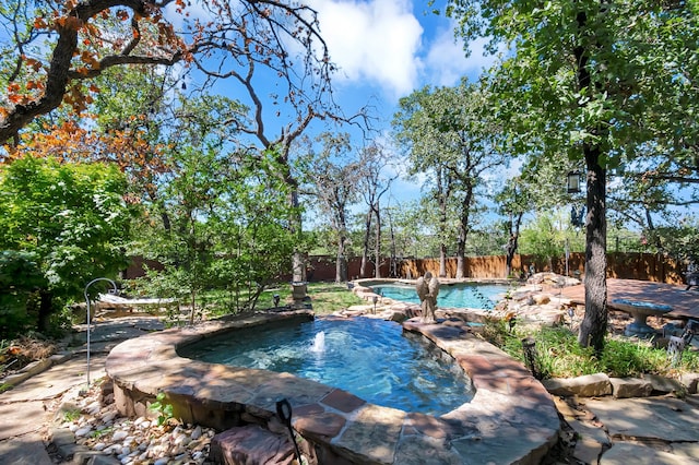 view of swimming pool with pool water feature and a hot tub