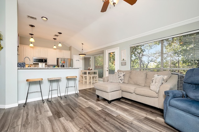 living room featuring lofted ceiling, light hardwood / wood-style floors, ceiling fan, and crown molding