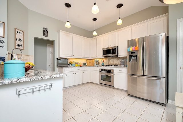 kitchen with appliances with stainless steel finishes, hanging light fixtures, tasteful backsplash, white cabinets, and light stone countertops