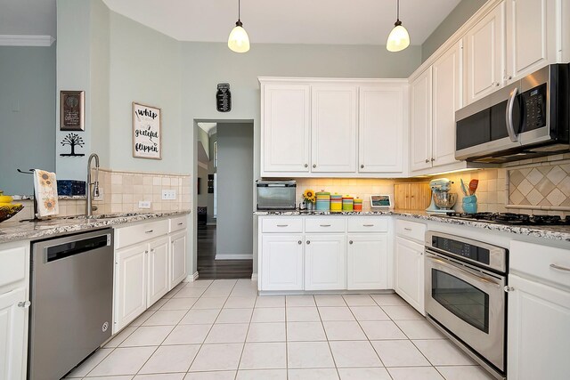 kitchen with white cabinets, light tile patterned floors, stainless steel appliances, vaulted ceiling, and decorative backsplash