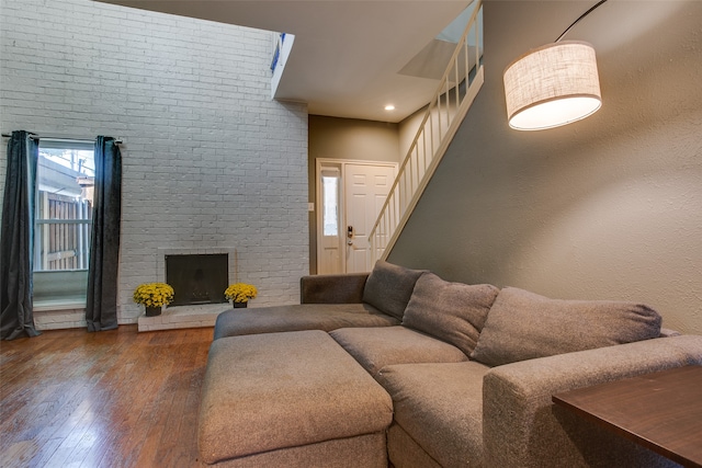 living room with wood-type flooring, a fireplace, and brick wall