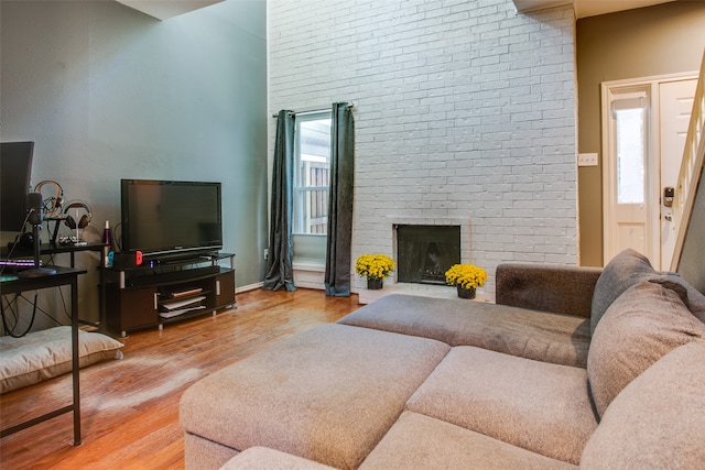 living room with brick wall, hardwood / wood-style flooring, and a fireplace