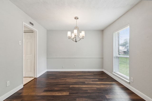 spare room with a chandelier, a textured ceiling, and dark hardwood / wood-style flooring