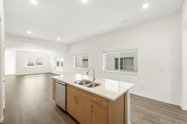 kitchen with stainless steel dishwasher, sink, light wood-type flooring, and a kitchen island with sink