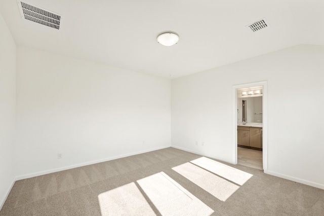 spare room featuring light colored carpet and lofted ceiling