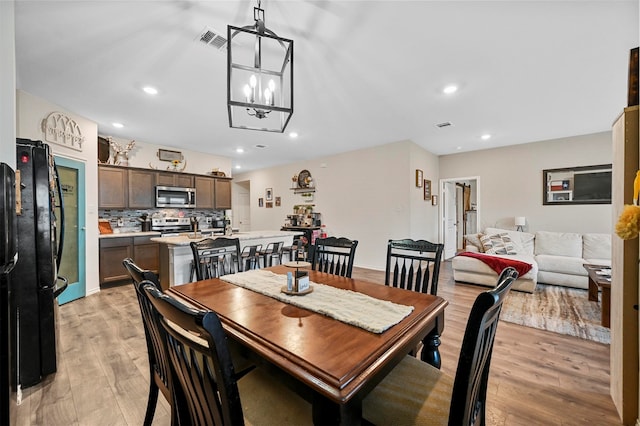 dining space with a notable chandelier and light hardwood / wood-style floors