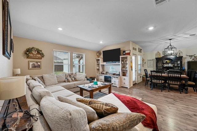 living room featuring lofted ceiling, an inviting chandelier, and hardwood / wood-style flooring