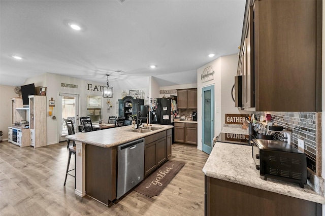 kitchen with light countertops, light wood-style flooring, a kitchen island with sink, appliances with stainless steel finishes, and a sink