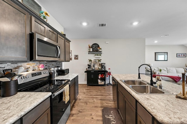 kitchen featuring light wood-style flooring, visible vents, appliances with stainless steel finishes, dark brown cabinetry, and a sink