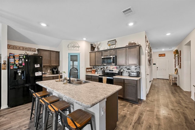 kitchen with a kitchen island with sink, sink, a kitchen bar, stainless steel appliances, and backsplash