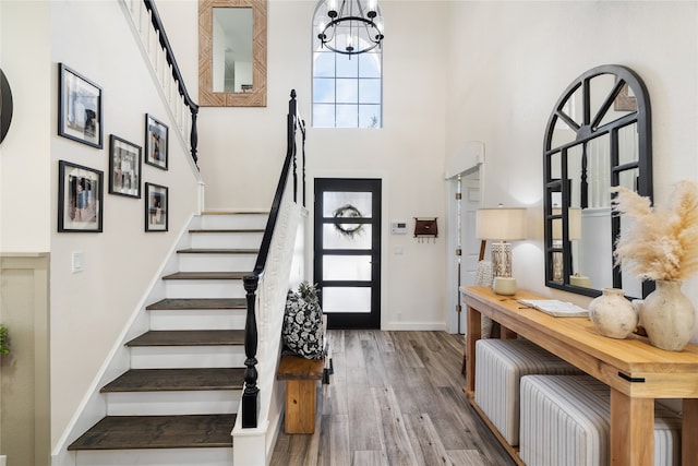 entrance foyer with a barn door, a high ceiling, an inviting chandelier, and hardwood / wood-style flooring