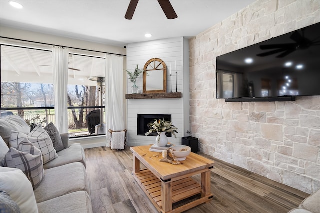 living room with a fireplace, ceiling fan, and hardwood / wood-style flooring