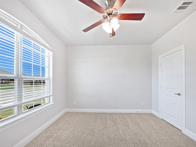 carpeted empty room with ceiling fan and plenty of natural light