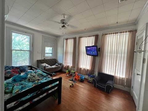 bedroom with wood-type flooring, crown molding, and ceiling fan