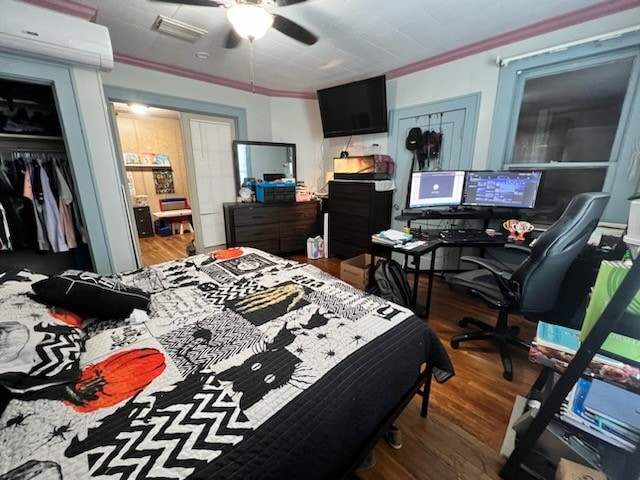 bedroom featuring crown molding, dark hardwood / wood-style floors, ceiling fan, and a wall mounted air conditioner