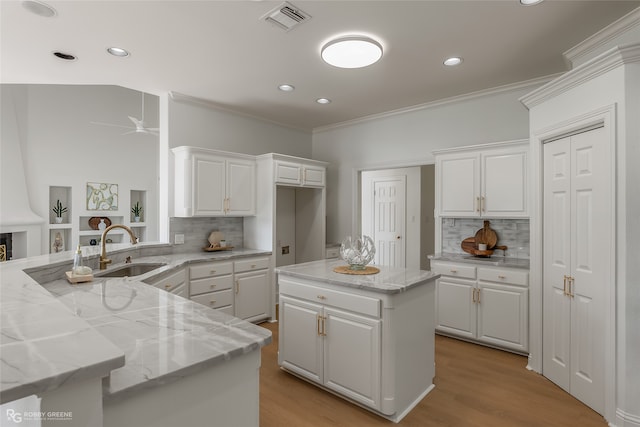 kitchen with ceiling fan, white cabinets, sink, and kitchen peninsula