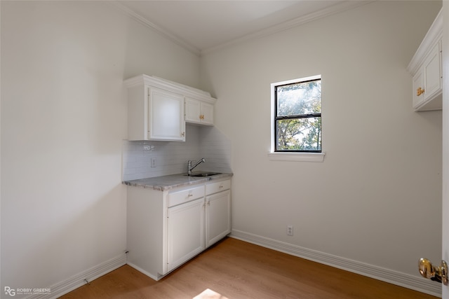 laundry room with sink, crown molding, and light hardwood / wood-style floors