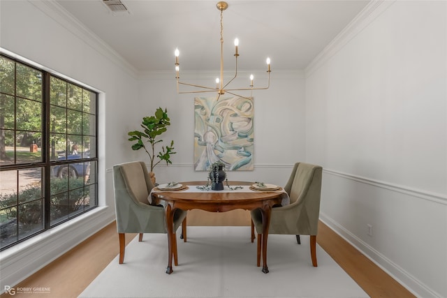 dining space with an inviting chandelier, crown molding, and hardwood / wood-style flooring