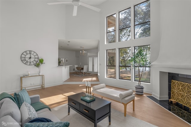 living room with a high ceiling, a large fireplace, a wealth of natural light, and hardwood / wood-style floors