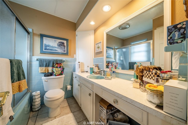 full bathroom with tile walls, shower / bath combination with glass door, tile patterned flooring, vanity, and toilet