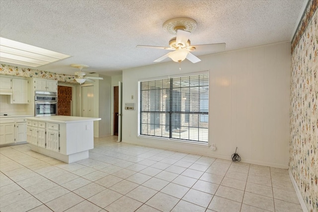 kitchen featuring light tile patterned floors, double oven, ceiling fan, and white cabinetry