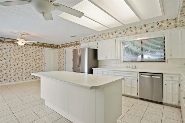 kitchen with white cabinetry, stainless steel appliances, a center island, ceiling fan, and sink