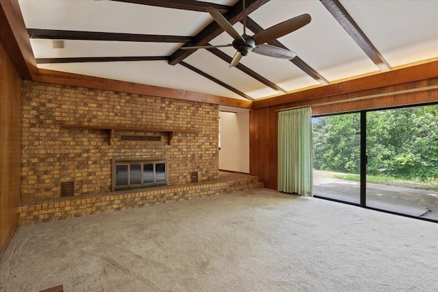 unfurnished living room with a brick fireplace, lofted ceiling with beams, carpet, and ceiling fan