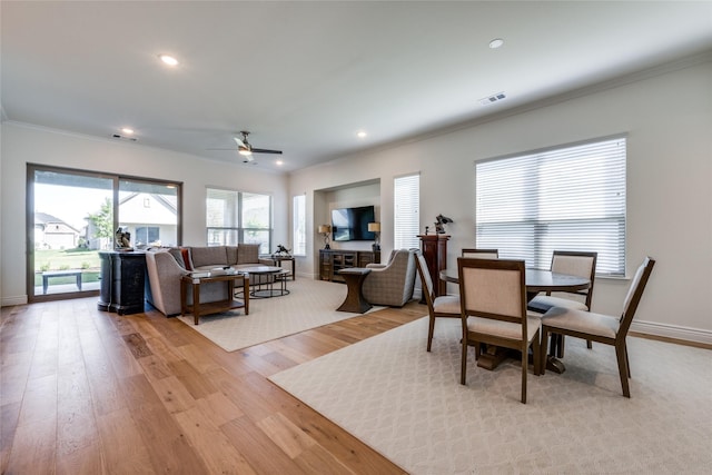 dining space with ceiling fan, crown molding, and light hardwood / wood-style flooring