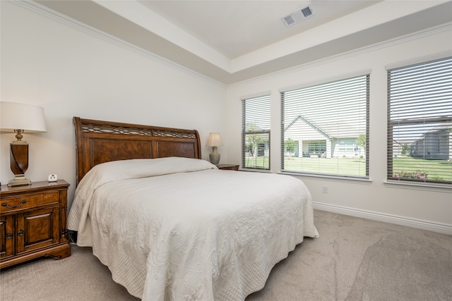 bedroom featuring a tray ceiling, light colored carpet, and ornamental molding