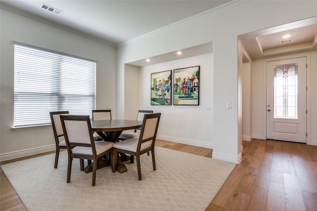 dining space featuring light wood-type flooring and ornamental molding