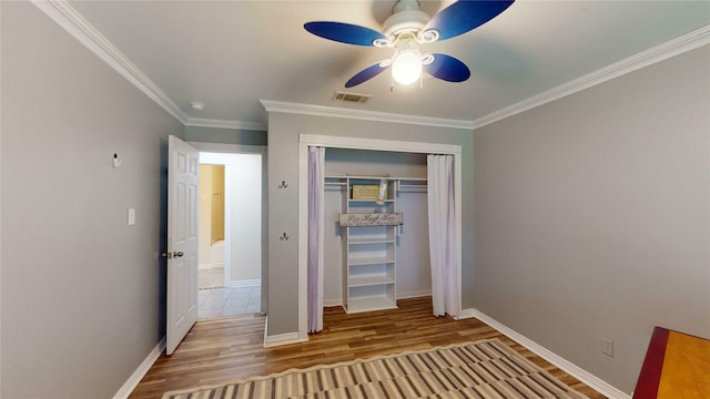 unfurnished bedroom with a closet, light hardwood / wood-style floors, ceiling fan, and crown molding