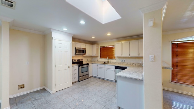 kitchen with ornamental molding, white cabinetry, a skylight, and appliances with stainless steel finishes