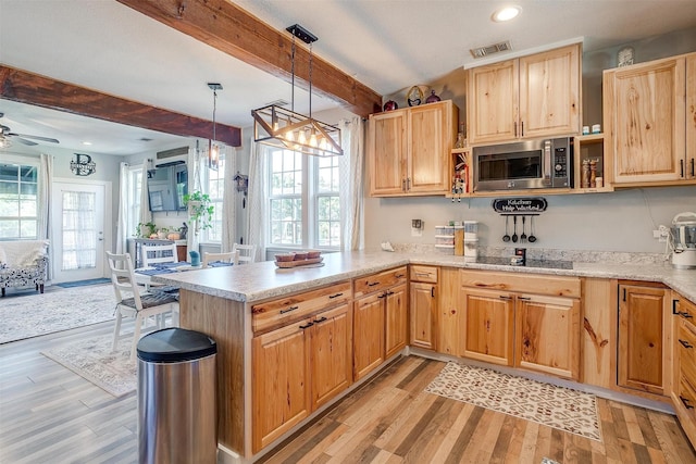 kitchen with black electric cooktop, a peninsula, beamed ceiling, stainless steel microwave, and decorative light fixtures