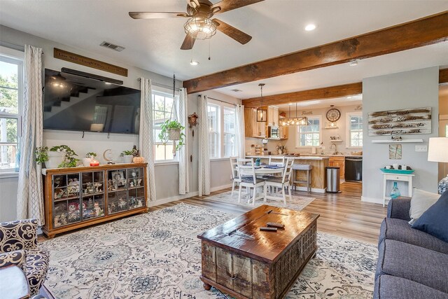 living area with a wealth of natural light, visible vents, and beamed ceiling