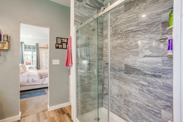 bathroom with a stall shower, baseboards, connected bathroom, and wood finished floors