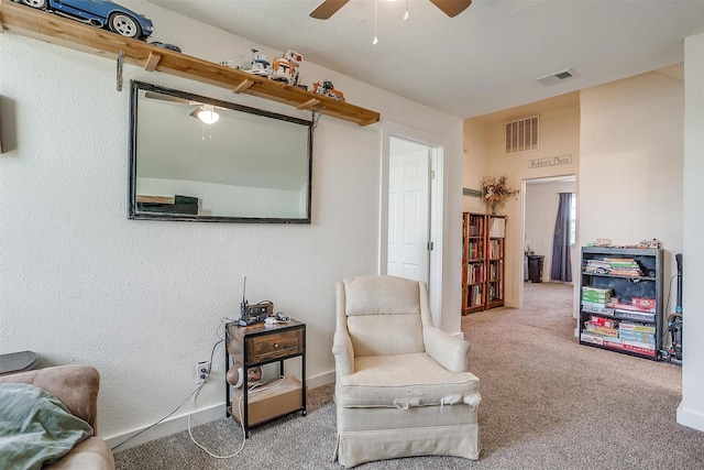 sitting room featuring a ceiling fan, baseboards, visible vents, and carpet flooring