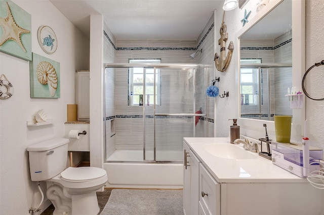 full bath with a wealth of natural light, combined bath / shower with glass door, vanity, and toilet