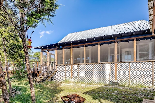 view of side of home featuring a sunroom, stairway, and metal roof