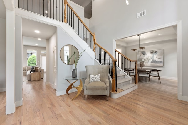 staircase with wood-type flooring and a towering ceiling