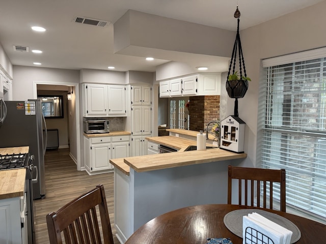 kitchen featuring white cabinetry, backsplash, kitchen peninsula, wooden counters, and gas stove