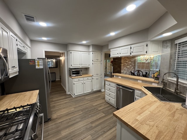 kitchen featuring white cabinets, butcher block counters, appliances with stainless steel finishes, and sink