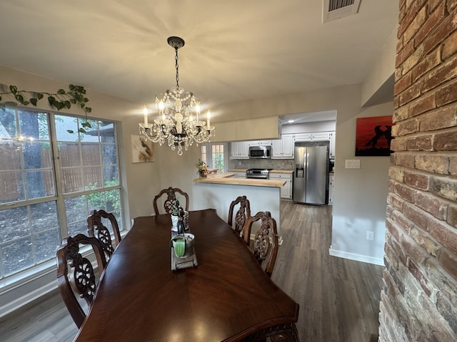 dining room with a notable chandelier, dark wood-type flooring, and a wealth of natural light