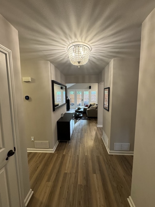 hallway featuring a notable chandelier, a textured ceiling, and dark wood-type flooring