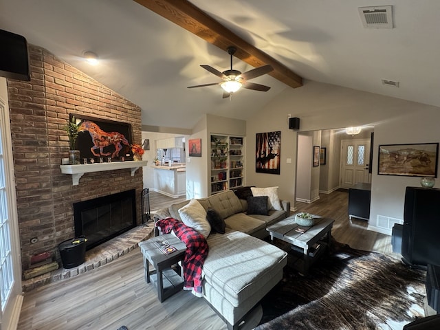 living room with wood-type flooring, vaulted ceiling with beams, ceiling fan, and a fireplace