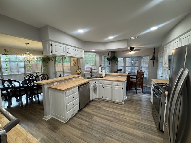 kitchen featuring appliances with stainless steel finishes, ceiling fan with notable chandelier, white cabinetry, and wood counters