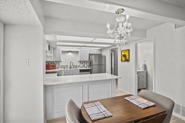 315 Highlander Hts, Hideaway, TX 75771 - dining room featuring a toaster, a chandelier, a textured ceiling, and light wood-type flooring
