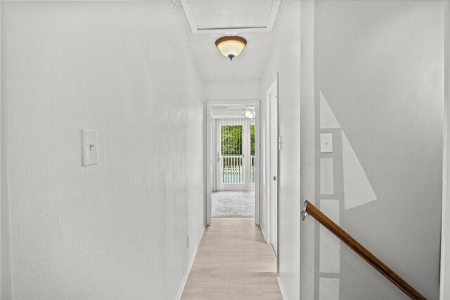 315 Highlander Hts, Hideaway, TX 75771 - corridor featuring attic access, a textured ceiling, light wood-type flooring, baseboards, and an upstairs landing